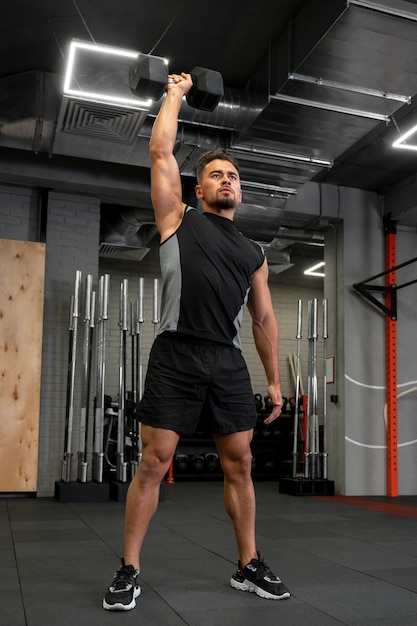 Attraktiver fitter Mann, der drinnen mit Hanteln trainiert