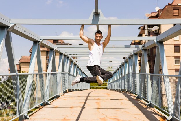Attraktiver junger Mann, der über der Decke der Brücke hängt