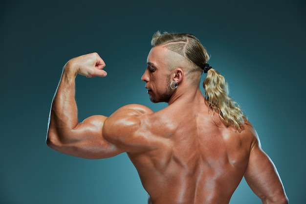 Attraktiver männlicher Bodybuilder, der Muskeln zeigt