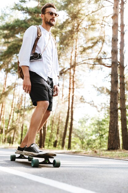 Attraktiver Mann auf Skateboard im Freien