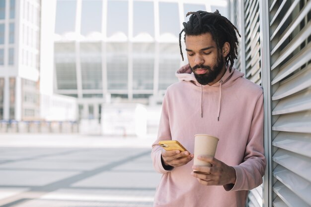 Attraktiver Mann, der auf Vorderansicht des Telefons schaut