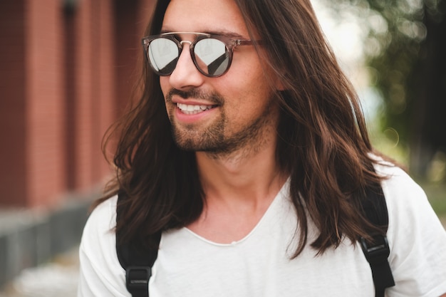 Kostenloses Foto attraktiver mann des porträts mit sonnenbrille auf dem städtischen szenenlächeln