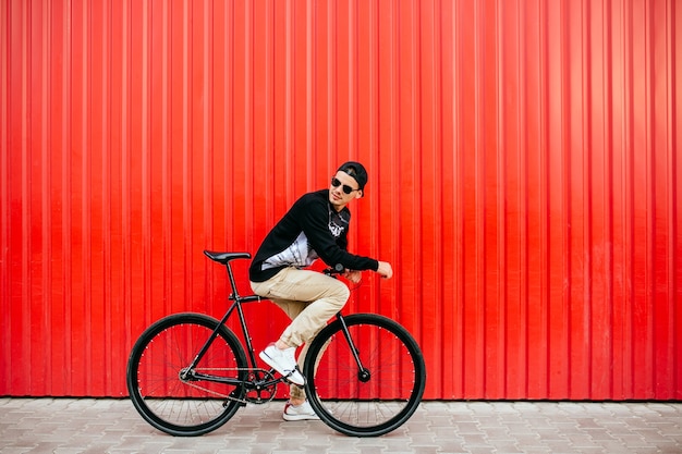 Kostenloses Foto attraktiver mann in der sonnenbrille, sitzend auf berufsfahrrad und reiten und zurück schauen