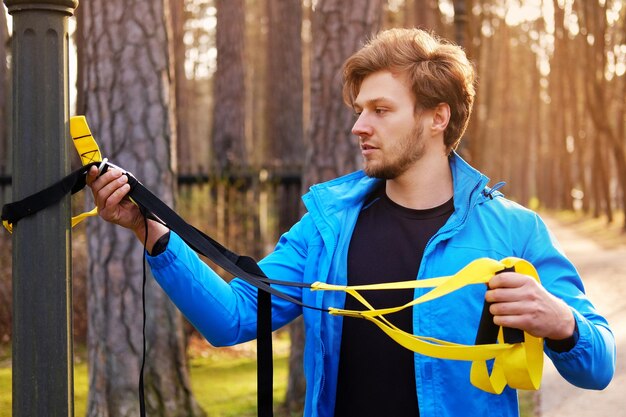 Attraktiver positiver Mann, der mit TRX-Fitnessstreifen trainiert.