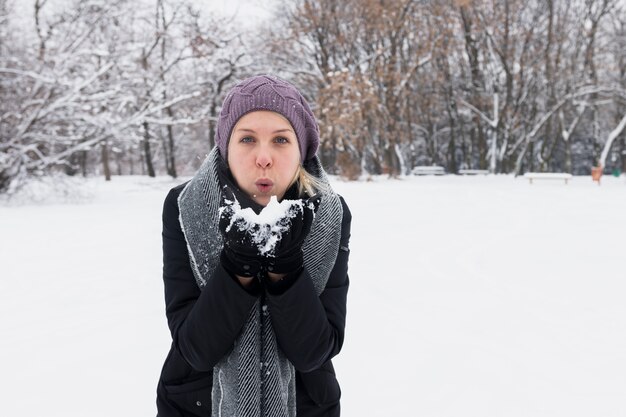 Attraktiver Schlagschnee der jungen Frau in der Winternatur