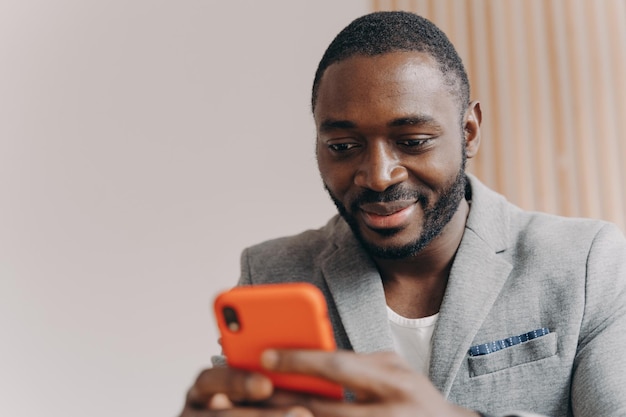 Attraktiver selbstbewusster junger afroamerikanischer selbstständiger, der mit partnern auf dem smartphone chattet