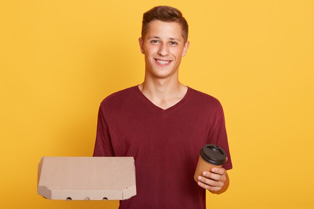 Attraktiver Typ mit Kaffee zum Mitnehmen und Karton mit Pizza