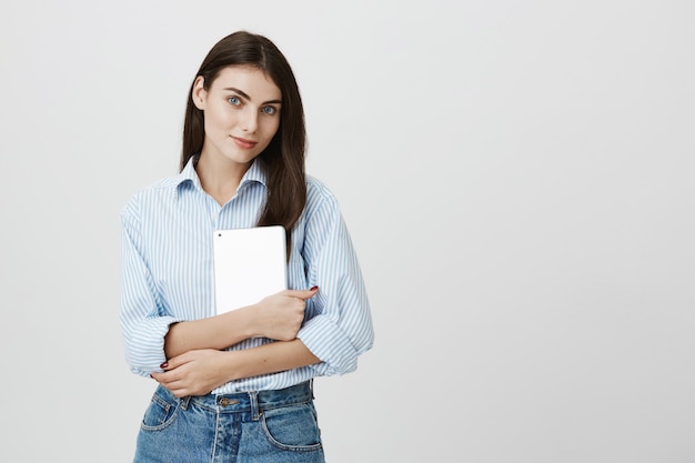 Attraktiver weiblicher Büroangestellter, der digitales Tablett hält und lächelt