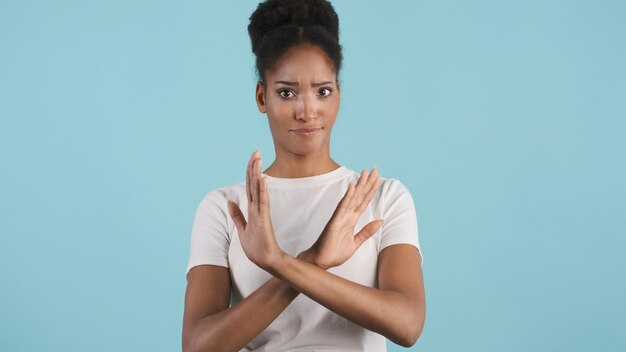 Attraktives afrikanisch-amerikanisches Mädchen mit gekreuzten Händen, das selbstbewusst keine Geste vor der Kamera vor buntem Hintergrund zeigt