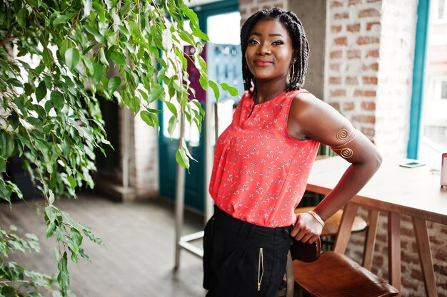 Attraktives afrikanisch-amerikanisches Mädchen posierte im Café gegen Baum