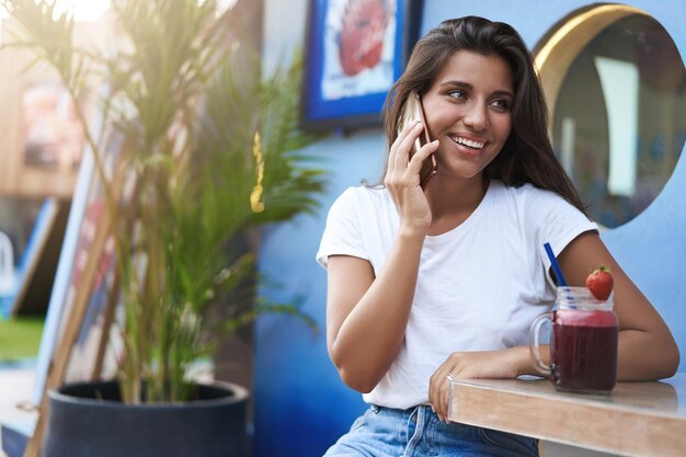 Attraktives gebräuntes europäisches Mädchen, das Straßencafé Tera im Freien sitzt