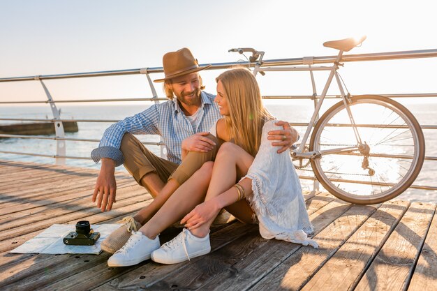 Attraktives glückliches lächelndes Paar, das im Sommer auf dem Seeweg auf Fahrrädern reist