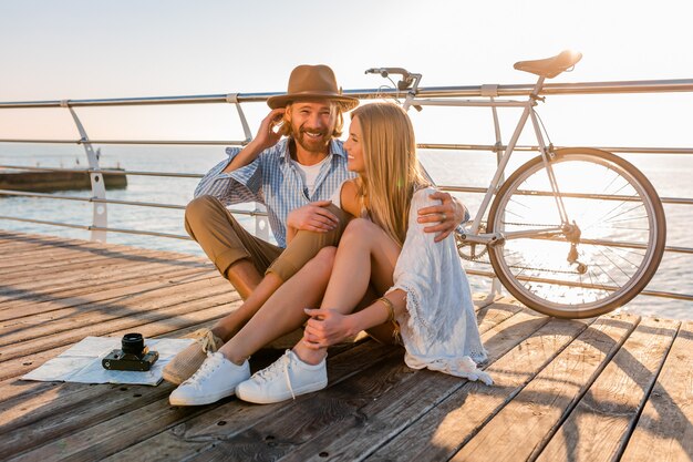 Attraktives glückliches Paar, das im Sommer auf dem Seeweg auf Fahrrädern, Boho-Hipster-Mode des Mannes und der Frau reist, die Spaß zusammen haben