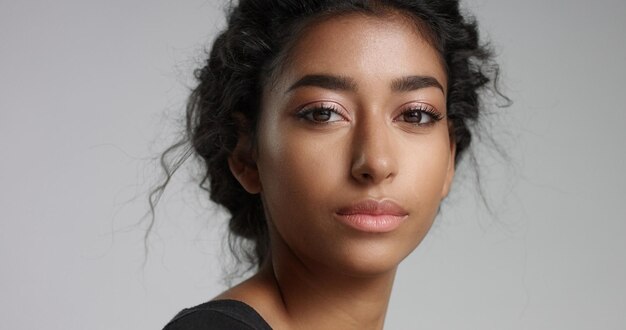 Attraktives junges Model aus dem Nahen Osten, das ihr hübsches Gesicht mit makelloser Haut berührt und lächelt