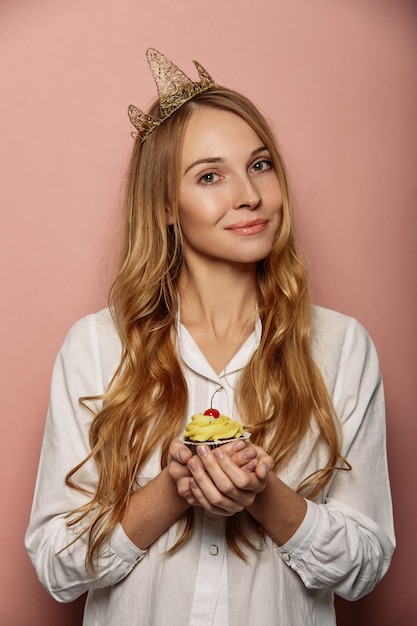 Attraktives Mädchen mit einer Krone und einem kleinen Kuchen