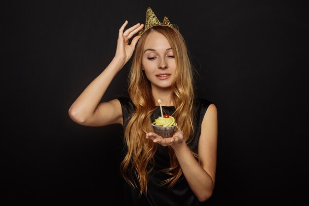 Attraktives Mädchen mit einer Krone und einem kleinen Kuchen