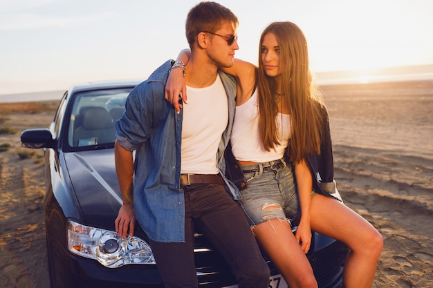 Attraktives Paar, das nahe Auto am Strand aufwirft.