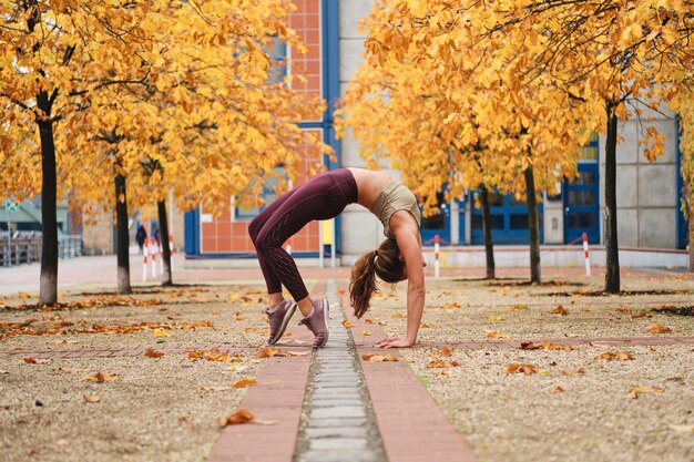 Attraktives sportliches Mädchen, das Brückenübungen während der Yogapraxis im Freien macht