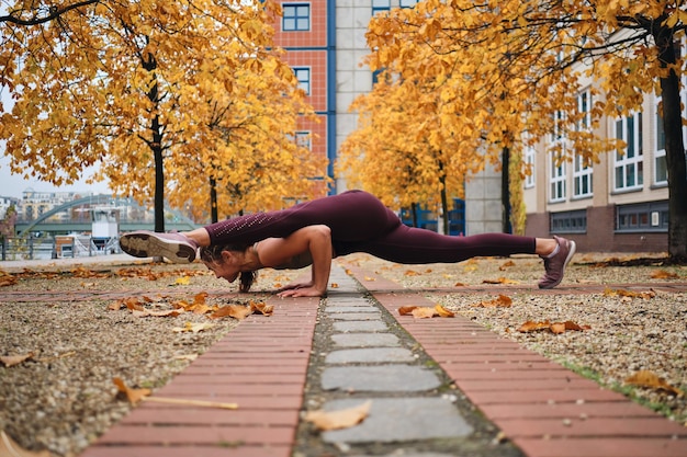 Attraktives sportliches Mädchen in Sportbekleidung, das Yoga-Übungen auf leerer Stadtstraße macht