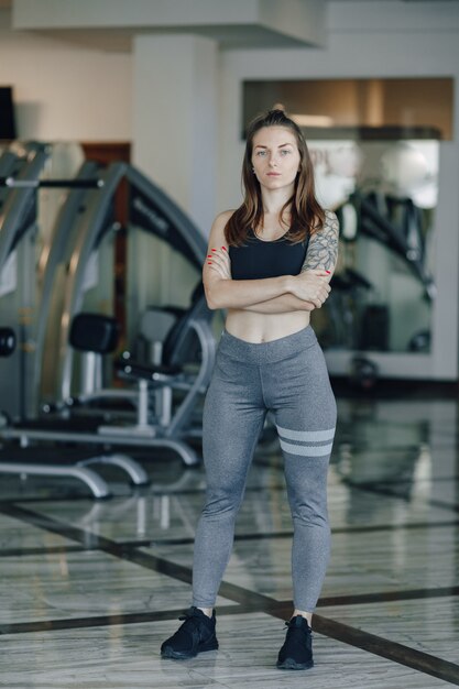 Attraktives sportliches Mädchen steht auf dem Hintergrund der Simulatoren im Fitnessstudio. gesunder Lebensstil.