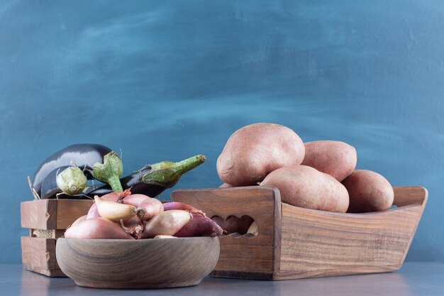 Auberginen, Kartoffeln und Zwiebeln in Holzkisten.