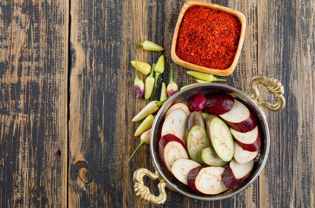 Auberginenscheiben in einer Pfanne mit Gewürzen, Paprika flach auf Holz legen