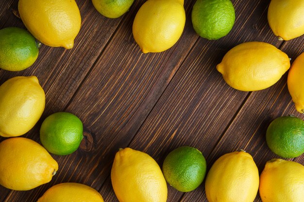 Auf einem Holztisch lagen verstreute Zitronen mit flachen Limetten