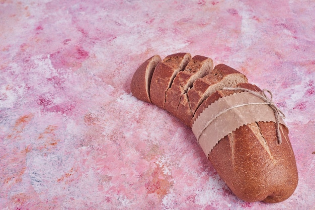 Auf einem rosa Tisch geschnittenes Brot.