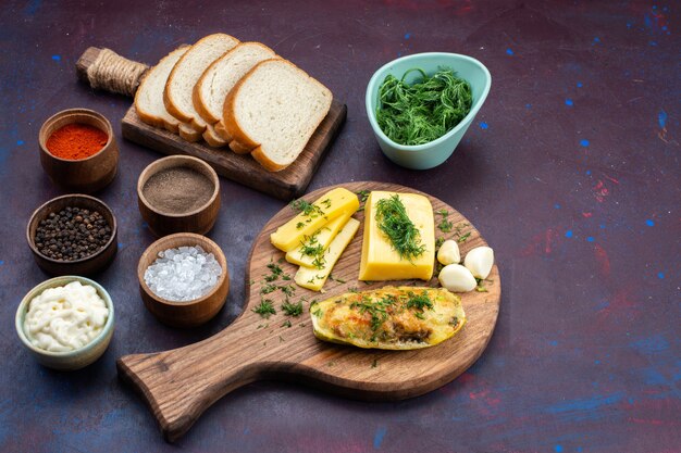 Auf halber Draufsicht gekochte leckere Kürbisse mit Gewürzen, grünem Käse und Brotlaib auf einem dunkelvioletten Schreibtisch.