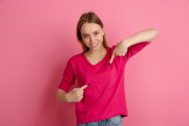 Auf sich selbst zeigend. Kaukasisches Porträt der jungen Frau lokalisiert auf rosa Wand, Monochrom. Schönes weibliches Modell. Konzept der menschlichen Emotionen, Gesichtsausdruck, trendy.