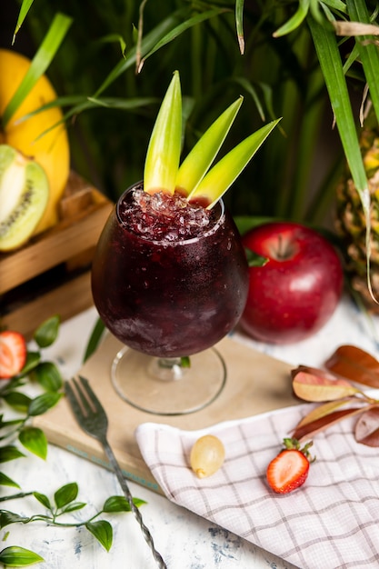 Auffrischungssommer alkoholischer Cocktail Margarita mit zerstoßenem Eis und Zitrusfrüchten innerhalb des Glases mit Erdbeeren und Apfel auf Küchentisch