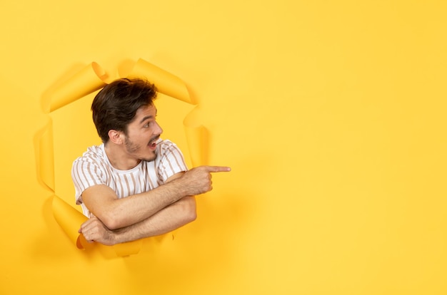 Aufgeregt junger Mann, der auf einem zerrissenen gelben Papierhintergrund steht