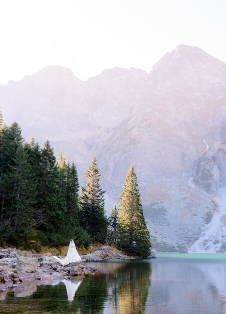 Aufgeregte Braut steht umgeben von der Schönheit des Hochlandsees und der Berge