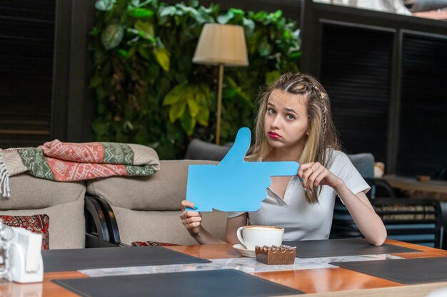 Aufgeregte Dame mit blauem Ideenbrett und Blick auf die Kamera im Restaurant