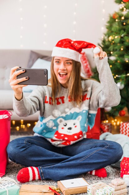 Aufgeregte Frau, die selfie mit Weihnachtshut nimmt