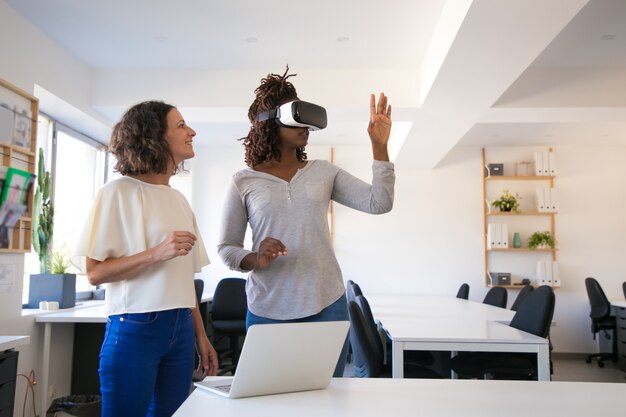 Aufgeregte Frau, die VR-Kopfhörer mit Assistenten prüft