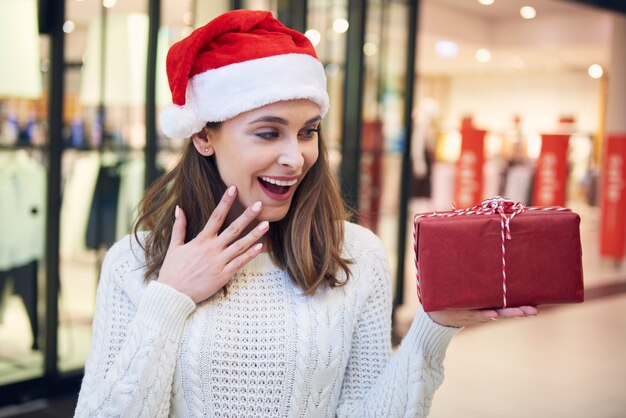 Aufgeregte Frau, die Weihnachtsgeschenk betrachtet