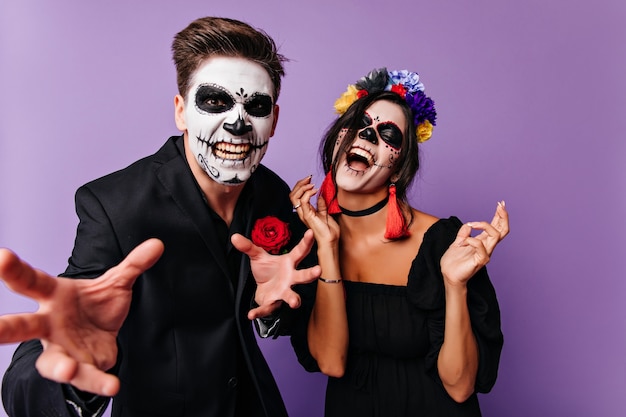 Aufgeregte Frau in Zombiekleidung scherzt mit Freund. Positive junge Leute, die in Halloween herumalbern.