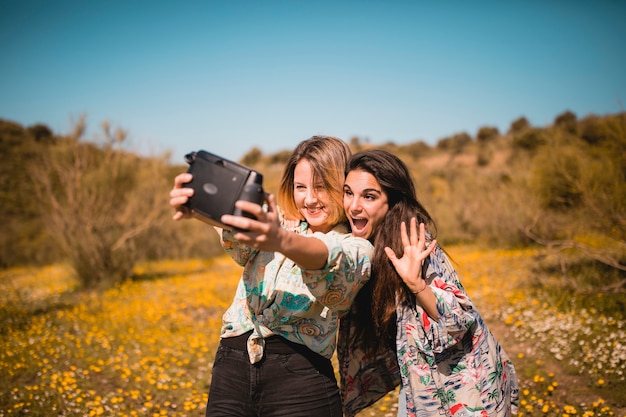 Aufgeregte Frauen, die selfie in der Wiese nehmen