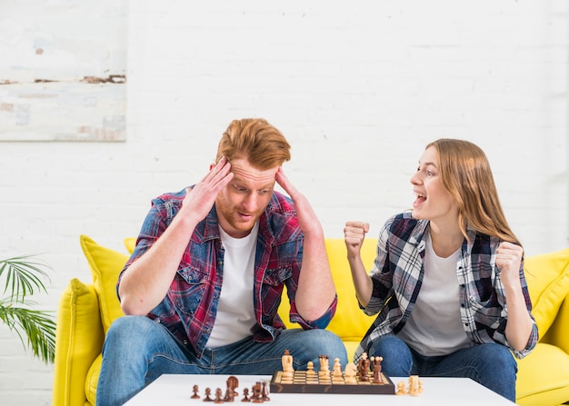 Aufgeregte junge Frau, die mit ihrem Freund zujubelt, nachdem das Schachspiel gewonnen worden ist