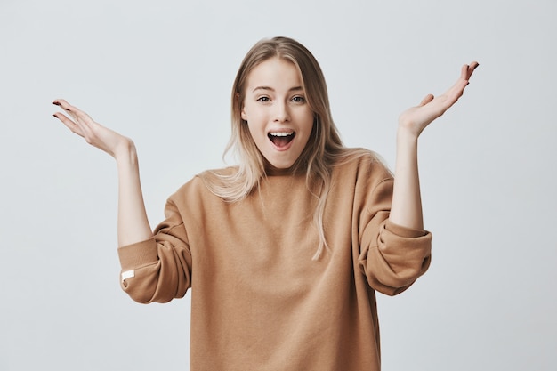 Aufgeregte junge Frau mit blonden Haaren ausrufend. Positive Emotionen, Mimik