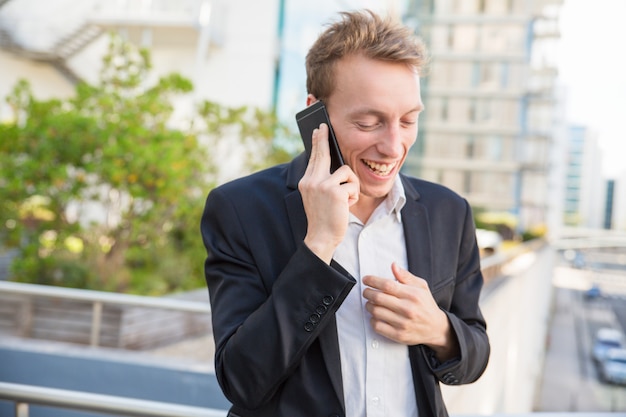 Aufgeregter froher Geschäftsmann, der am Telefon plaudert