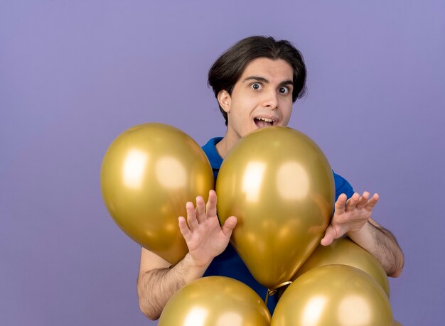Aufgeregter gutaussehender kaukasischer Mann steht mit Heliumballons, die die Hände ausstrecken