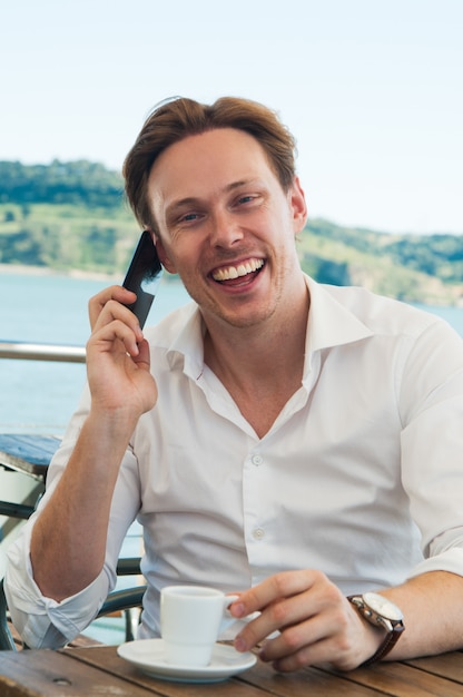 Aufgeregter junger lachender Mann bei der Unterhaltung am Telefon