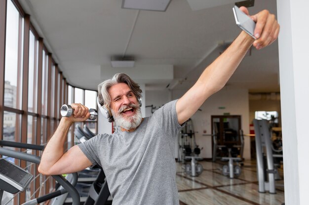 Aufgeregter Mann, der Selfies im Fitnessstudio nimmt