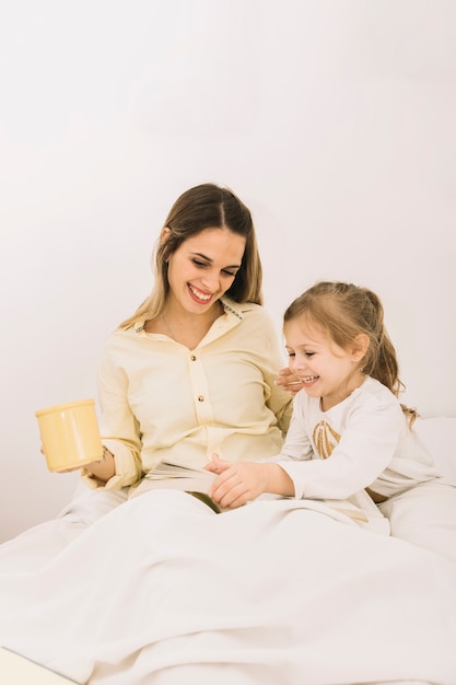 Aufgeregtes frauenlesebuch mit tochter auf bett