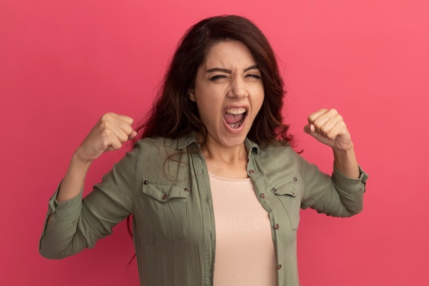 Aufgeregtes junges schönes Mädchen mit olivgrünem T-Shirt mit Ja-Geste isoliert auf rosa Wand pink