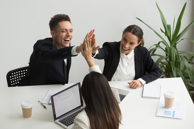 Aufgeregtes tausendjähriges Büroteam, das zusammen hoch fünf, Teambuildingkonzept gibt