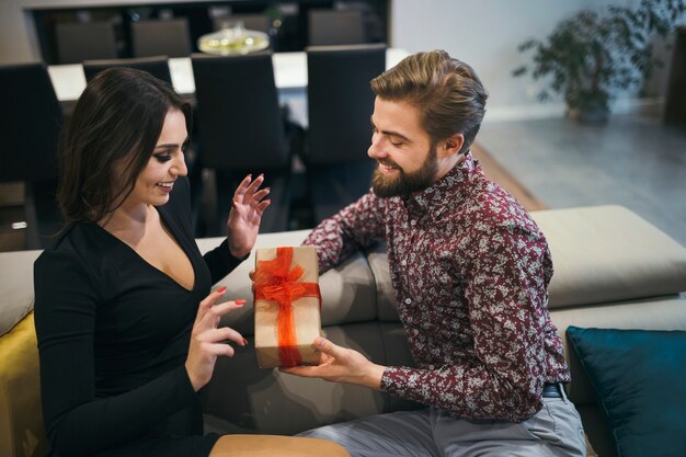 Aufmerksamer Mann, der der Frau Geschenk gibt