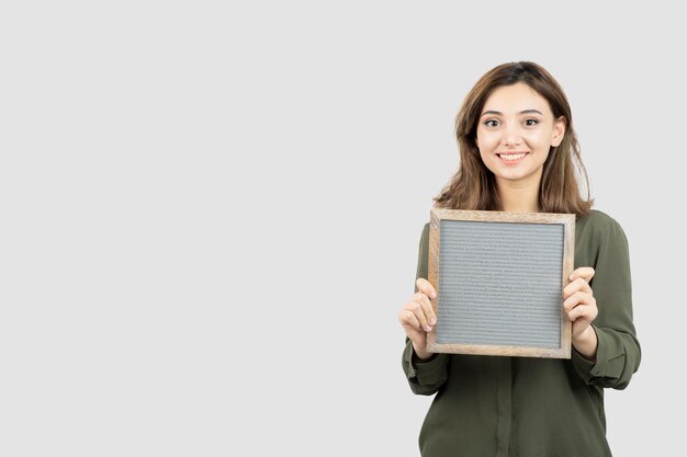 Aufnahme einer entzückenden jungen Frau, die einen leeren Rahmen über Weiß zeigt. Foto in hoher Qualität